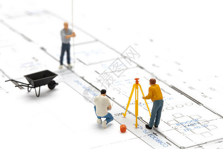 迷你测量员技术员正在测量用绘图计划建造房屋的距离图片