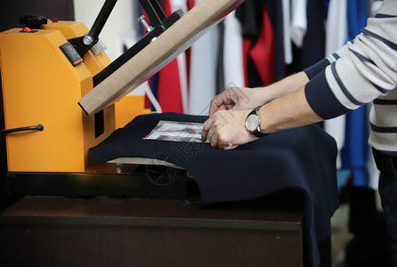 店标素材男子准备T恤衫在丝绸屏幕印刷机中背景