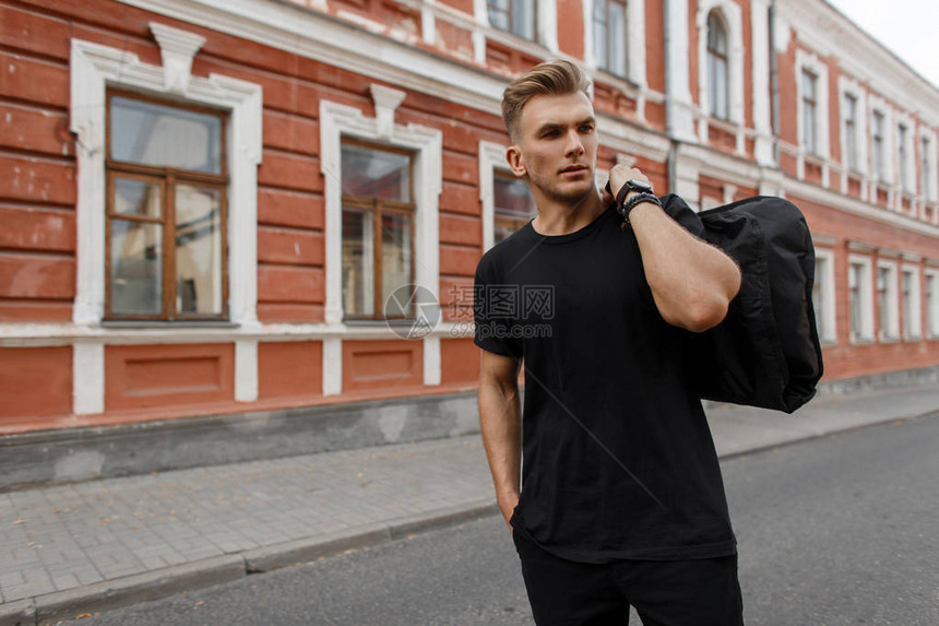 漂亮的年轻时尚模特男穿着黑色T恤的发型肩膀上穿黑袋图片