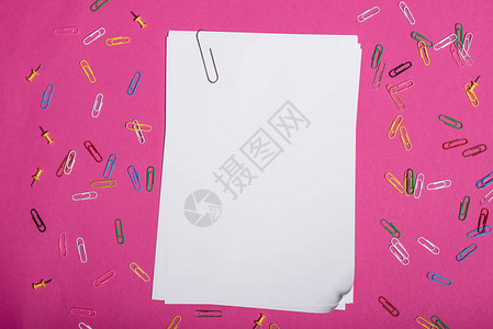 在粉红色上隔离的空白皮书和彩色纸夹的顶部视图背景图片