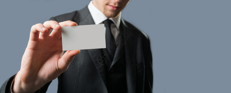 年轻商人拿着空白的卡来显示他的资质和资格背景图片