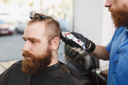关闭由理发师为客户服务的男专业美发师图片