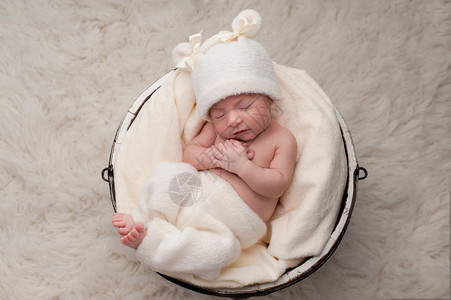 鹤唳九天睡在白木桶里的九天大的婴儿女婴穿着自行车裤和一顶相配的帽背景