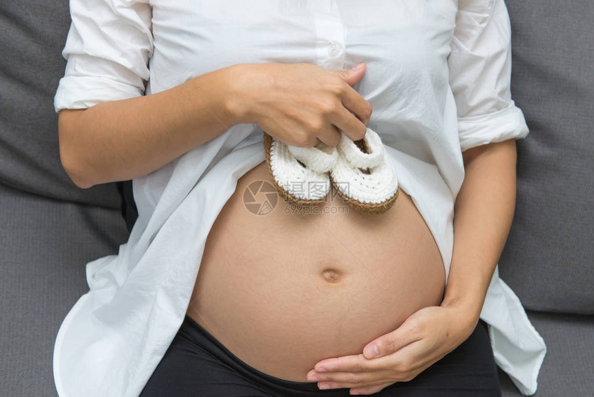 孕妇腹部婴儿的鞋小怀孕妇女图片