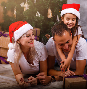 在家圣诞树旁躺着可爱快乐家庭的特写图片