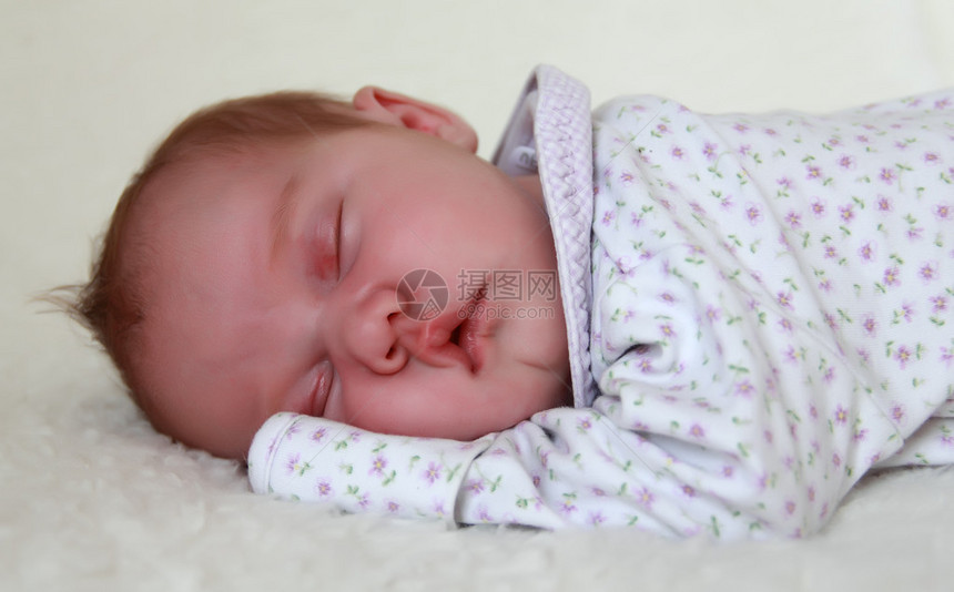 每月的婴儿睡在一条白色的毯子上图片
