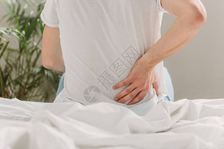 人坐在床上时触摸肠子和受伤害的景象图片