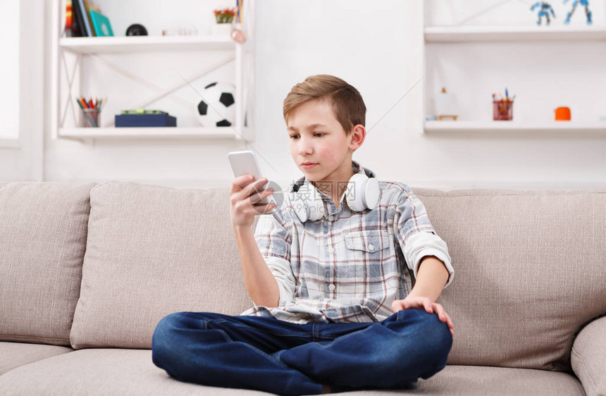青少年在家里客厅的沙发上通过手机向朋友聊天图片