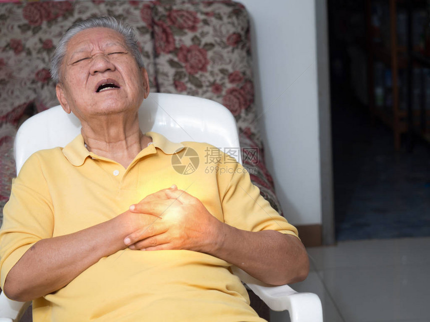 老年亚洲男子坐在的椅子上心脏病发作图片