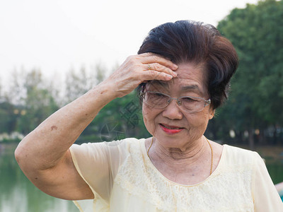 这位年长的亚裔妇女戴着一副眼镜她对头痛感到不舒服当老年妇女在图片
