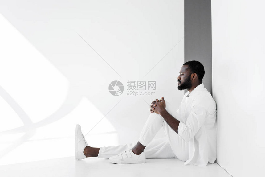 穿着白衣服坐在地板上的英俊时尚的非图片