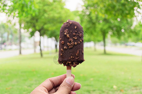 厚涂芒果手握冰淇淋上面涂着巧克力在自然背景