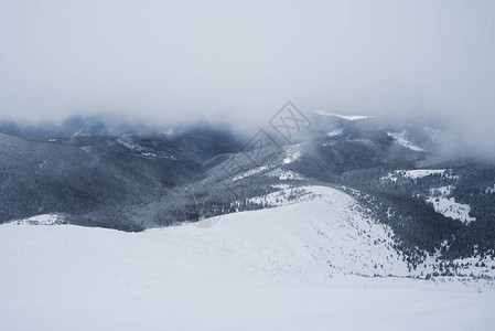 云层下的山势冬季风景和雪坡高清图片