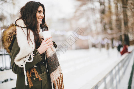 在寒冷的冬天在户外喝一杯热饮的快乐女人图片
