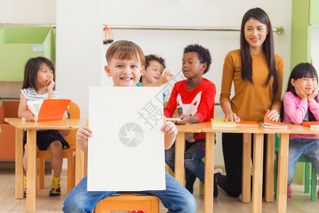 可爱男孩在幼儿园课堂上拿着满脸笑的空白海报幼稚园教育概念效应风格照片图片