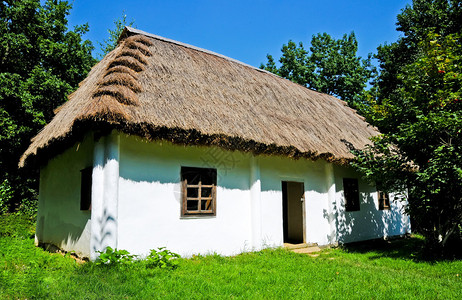 有白色墙壁和茅草屋顶的小屋背景图片