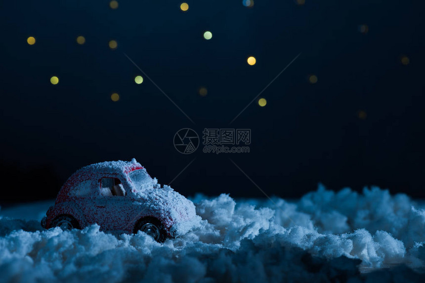 午夜在星空下站在雪中的玩具车近距离拍图片