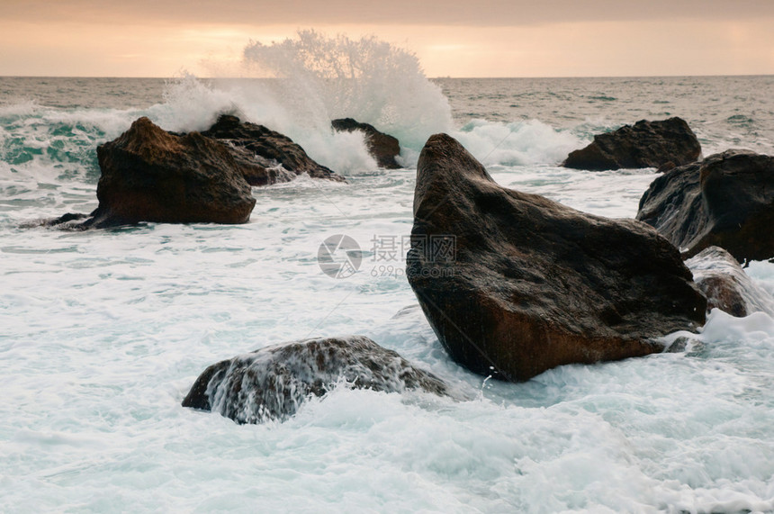 海上风暴海岸附近的岩石上出现大浪图片