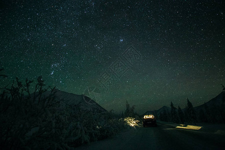 站在冬季路上的汽车和夜晚山上美丽的星图片