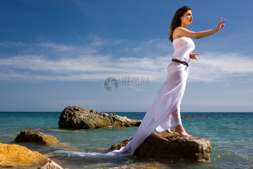 在海滩上穿着白色连衣裙的美丽女人图片