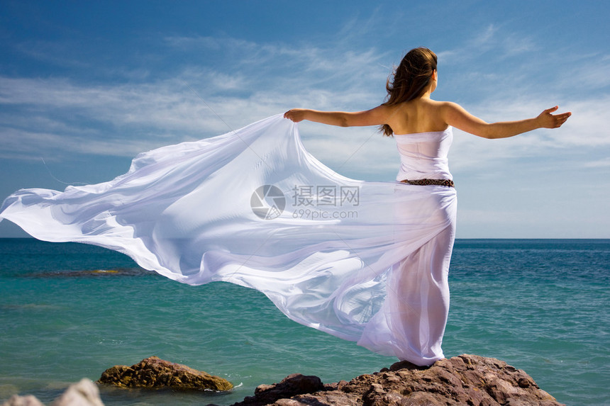在海滩上穿着白色连衣裙的美丽女人图片