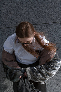一个戴眼镜的时装女孩穿着毛皮大衣在城市阳光明图片