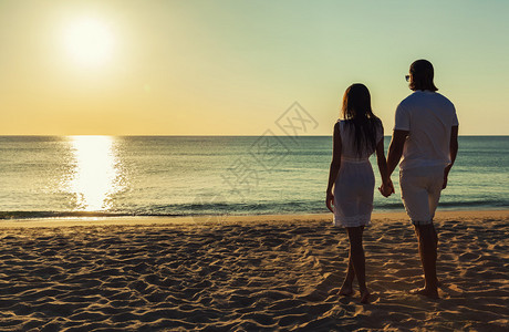 幸福的情侣牵手走在沙滩上看日落图片