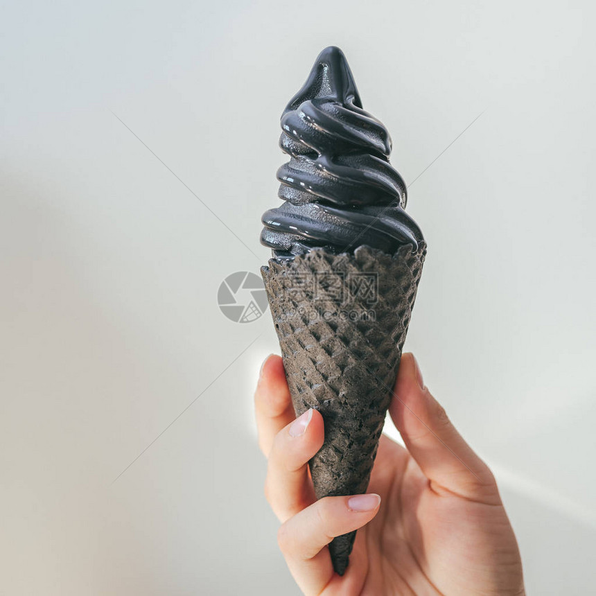 拿着黑冰淇淋背景模糊图片