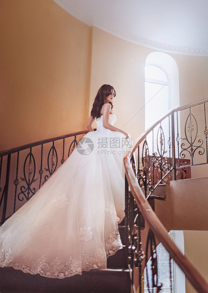 穿着白裙子站在楼梯上的漂亮新娘化妆打扮时图片