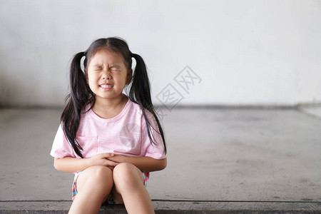 亚洲儿童可爱或小女孩坐在肚子痛图片
