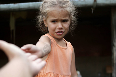 迷人的哭着泣的学龄前女孩伸出手臂请求帮助图片
