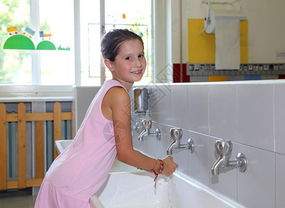 漂亮的小女孩洗手在陶瓷池里洗手在学校图片