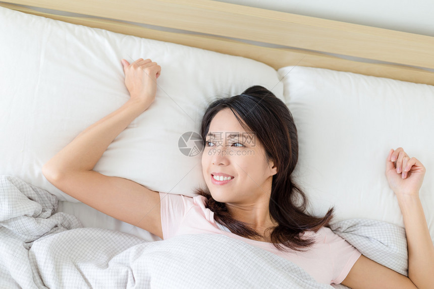 亚裔年轻妇女在床上醒图片