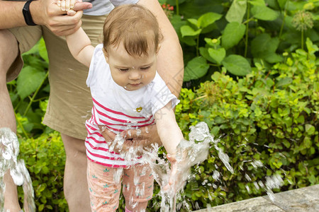 欧洲女婴在喷泉中玩水射流婴儿在喷泉里弄湿了她的手白人女孩玩水背景图片