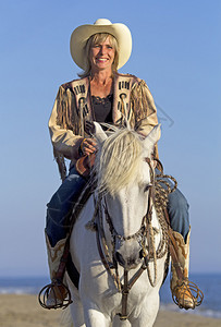 一名女牛仔在沙滩上骑着马图片