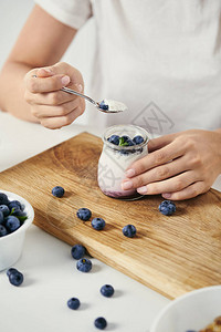 在桌顶用酸奶和新鲜蓝莓在木制剪板上早餐图片