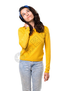 头戴黄色毛衣和蓝色头巾的小女孩站着思考一个想法图片