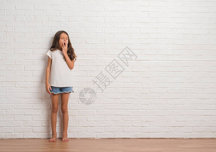 年轻的西班牙小孩在白砖墙上挥舞图片