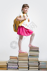 身背包的聪明女孩站在书本堆积图片