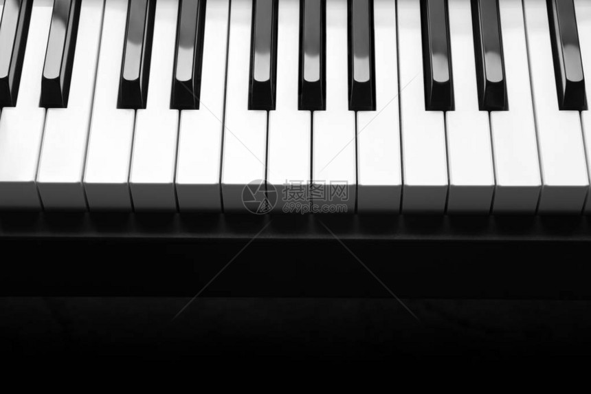 在深色背景上带有白色和黑色钢琴键的钢琴图片
