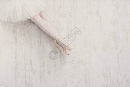 白色木地板上穿着尖头鞋的年轻芭蕾舞演员腿的特写镜头图片