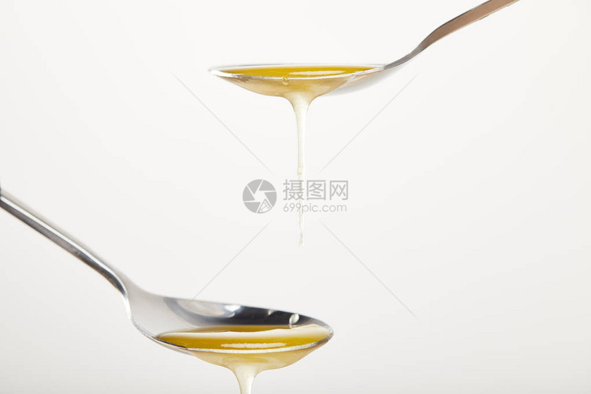 白色背景上加蜂蜜的勺子的特写视图图片