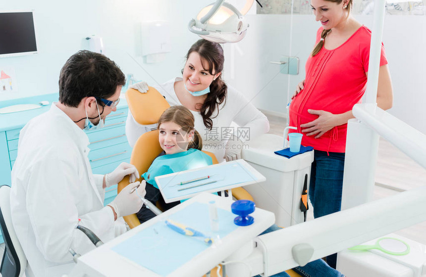 在其办公室治疗全家人孕妇和婴儿的牙科医生图片