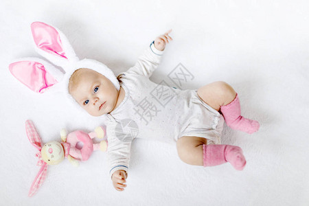 可爱的可爱新生女婴穿着复活节服装和耳朵可爱的孩子在玩毛绒玩图片