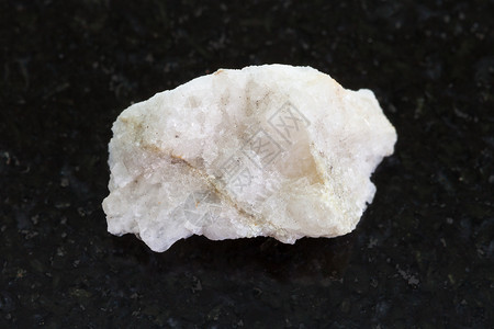 深色花岗岩背景粗石中天然矿物岩石标本白钨矿脉图片