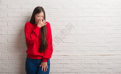 年轻女人在砖墙上闻到臭味恶心不可容忍的气味图片