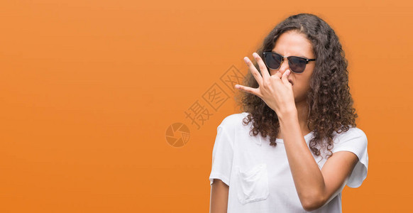 穿墨镜的年轻女神闻着臭味恶心难以忍受的气味用手指在鼻子上屏住呼吸图片