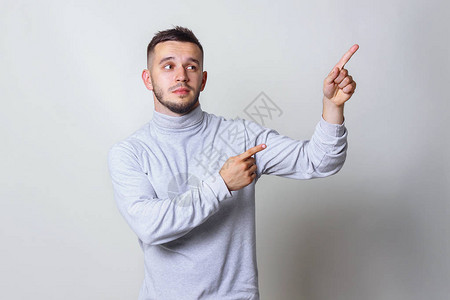 指向或显示方向的年轻人男子双手指向框架灰色背景复制图片