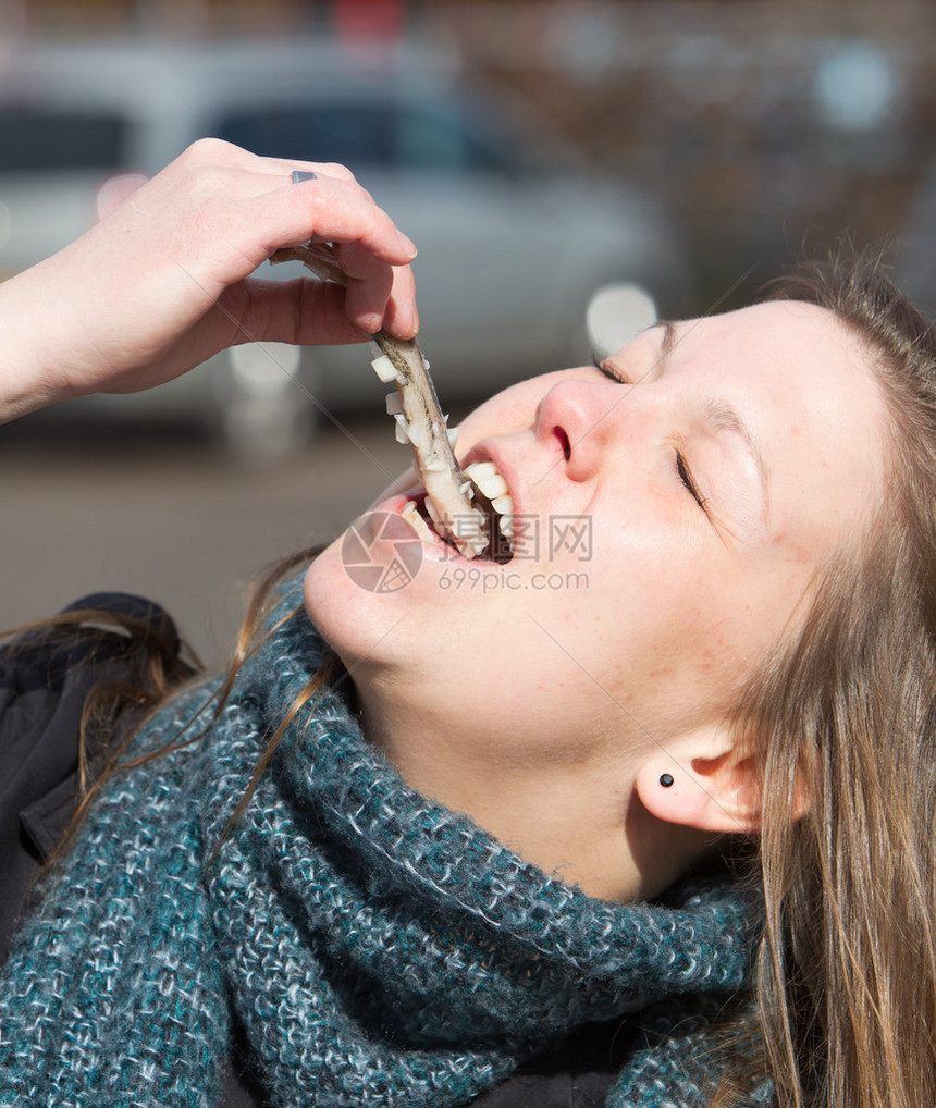 荷兰女人正在吃典型的生鲱鱼和洋葱图片