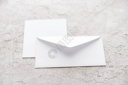 灰色纹理表面上的白纸信封和卡片背景图片